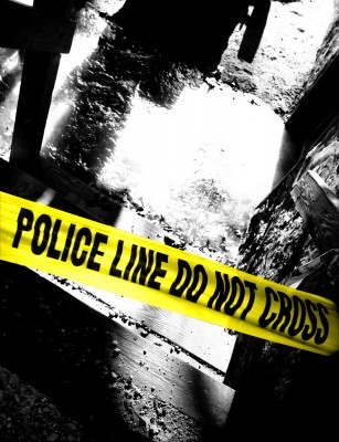 Close-up of yellow police tape marked 'POLICE LINE DO NOT CROSS,' placed in a shadowy area.